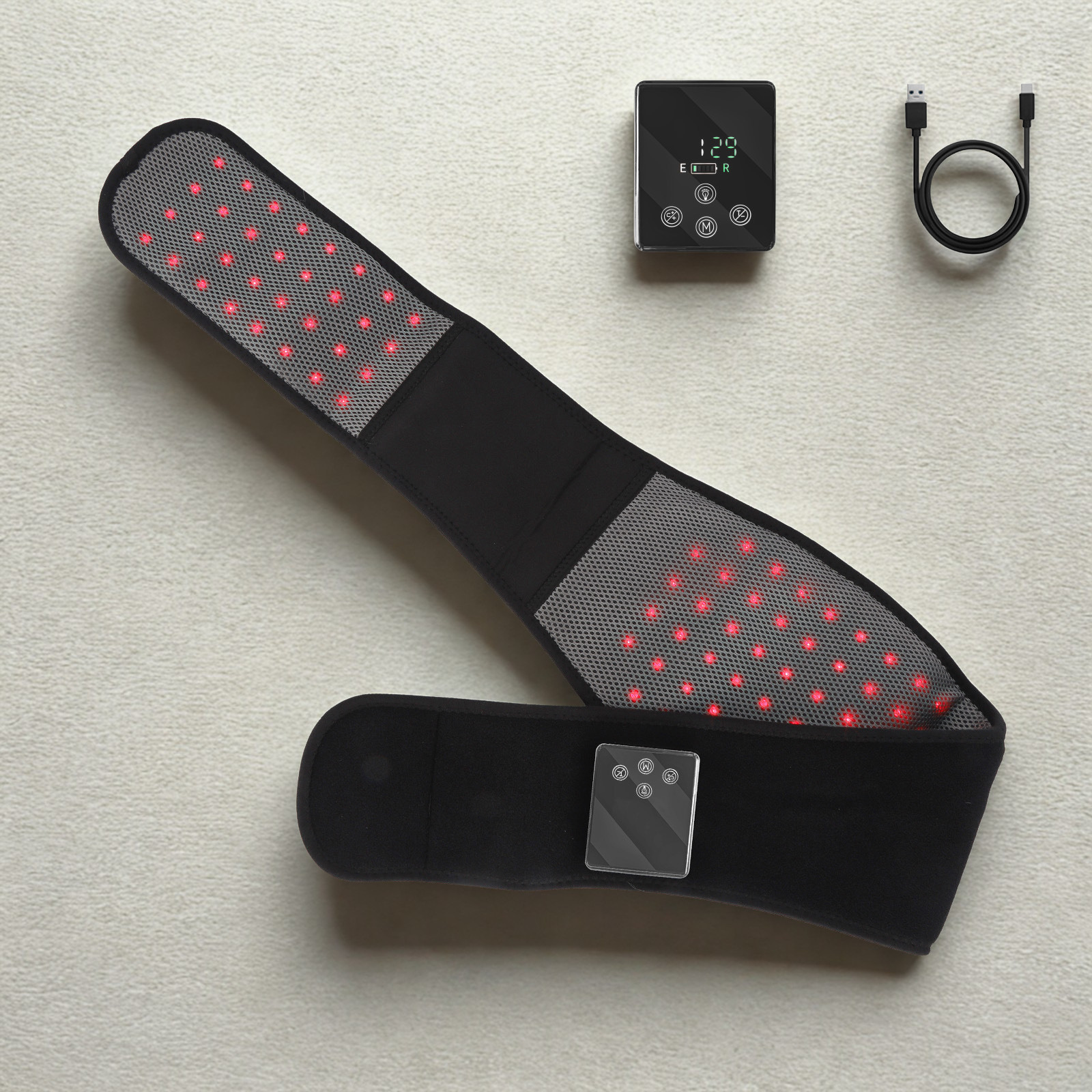 A black LED neck and shoulder massage belt with red light therapy panels, shown with its digital controller, power adapter, and USB cable on a light beige textured background.