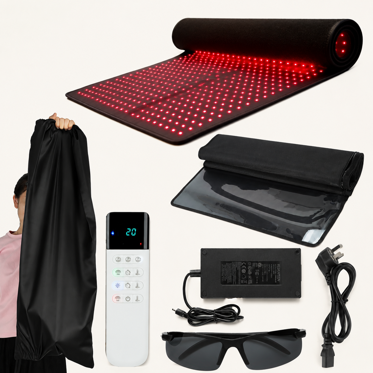 Red light therapy mat kit with a black carrying bag, white remote control, power adapter, cable, protective glasses, and a control panel, shown on a light background with a person holding the bag partially visible on the left.